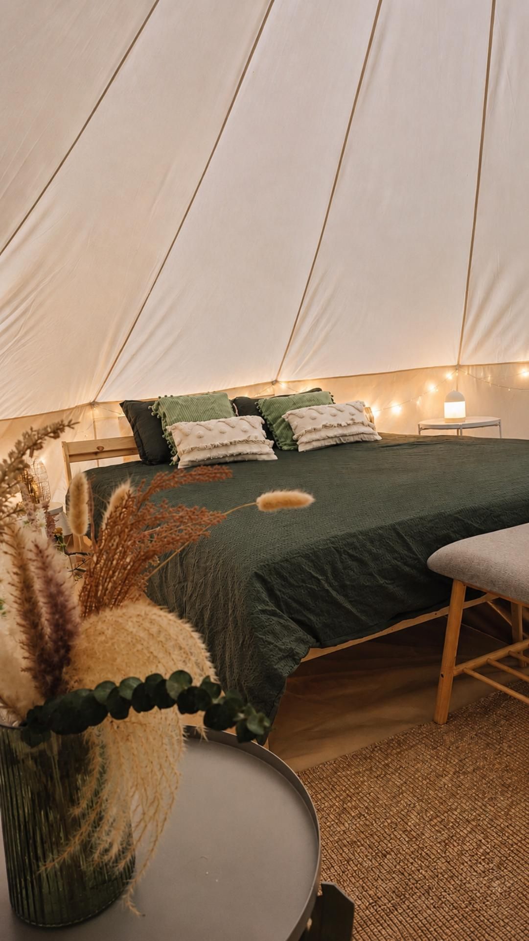 Ruime slaapkamer met tweepersoonsbed en sfeervolle verlichting in een luxe glamping bell tent
